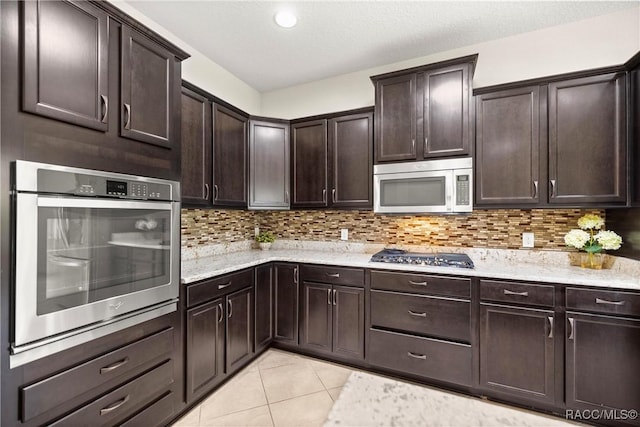 1825 W Caroline Path, Lecanto, FL 34461 - kitchen featuring stainless steel appliances, dark brown cabinets, light stone countertops, backsplash, and light tile patterned floors