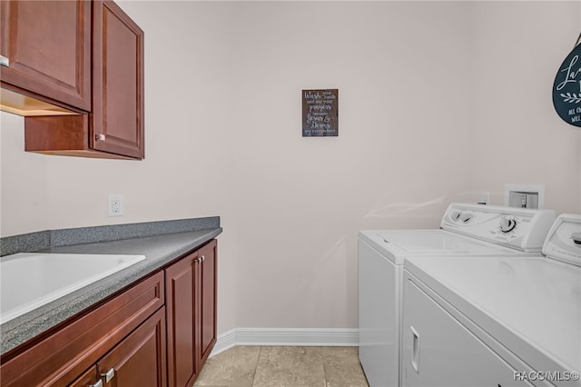 laundry area with cabinet space, a sink, washer and clothes dryer, and baseboards