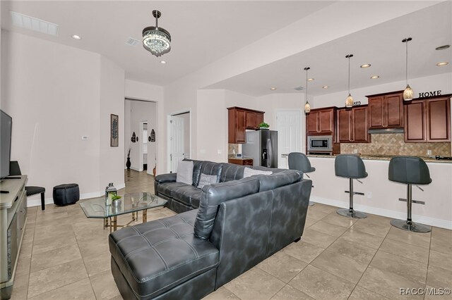 kitchen with a kitchen bar, decorative backsplash, stainless steel appliances, pendant lighting, and a chandelier