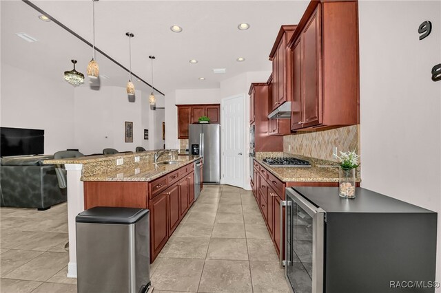 kitchen featuring sink, stainless steel appliances, an inviting chandelier, light stone counters, and backsplash