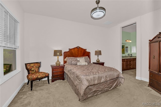 bedroom featuring light carpet, multiple windows, baseboards, and ensuite bathroom