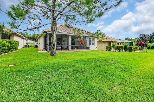 back of house featuring a sunroom, a tile roof, stucco siding, and a yard