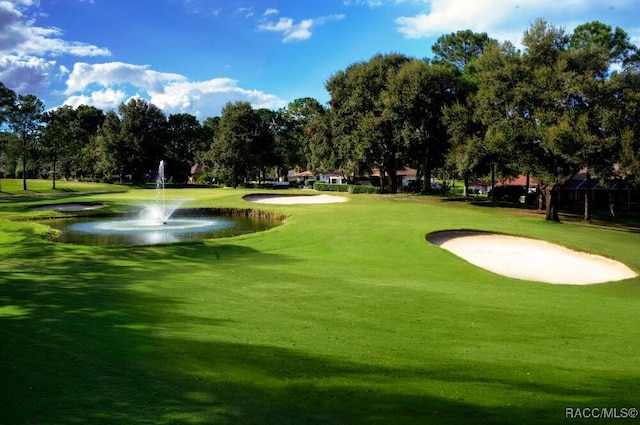 view of property's community with a yard, a water view, and view of golf course