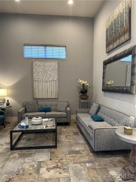 living room with a high ceiling and baseboards