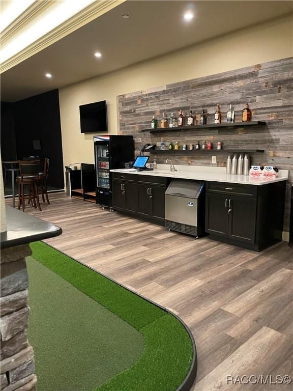 bar with light hardwood / wood-style flooring and wood walls