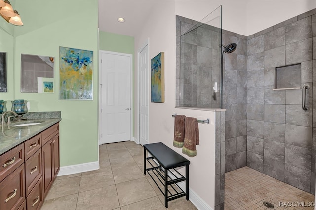 bathroom featuring tile patterned floors, baseboards, a walk in shower, and vanity