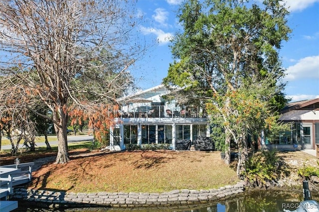 back of house with a water view and a lawn