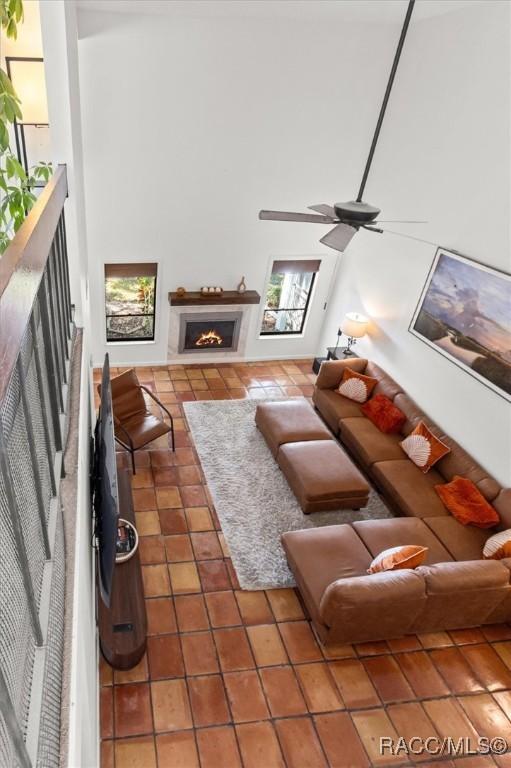 tiled living room featuring ceiling fan and a high ceiling