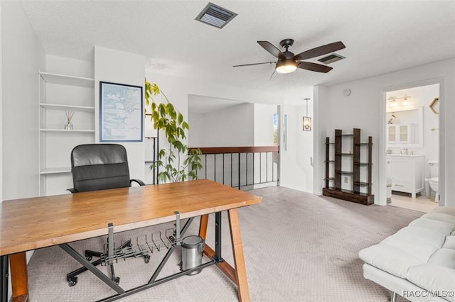 carpeted office space featuring a textured ceiling and ceiling fan