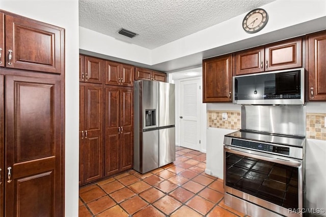 kitchen with a textured ceiling, light tile patterned floors, appliances with stainless steel finishes, and tasteful backsplash