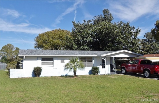 ranch-style house with an attached carport, roof with shingles, and a front yard