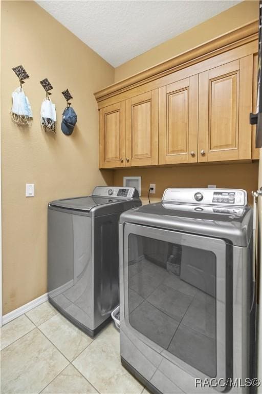 laundry area with cabinets, light tile patterned flooring, and washer and clothes dryer