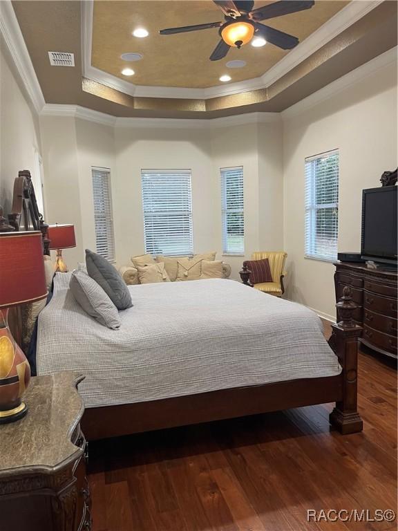 bedroom featuring ceiling fan, crown molding, dark hardwood / wood-style floors, and a raised ceiling