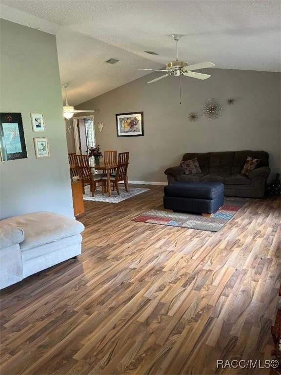 living room with wood-type flooring, a textured ceiling, ceiling fan, and lofted ceiling