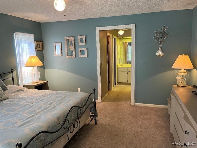 carpeted bedroom with ensuite bath and a textured ceiling