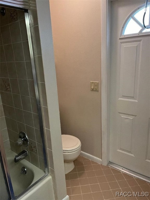 bathroom with tile patterned floors, tiled shower / bath combo, and toilet