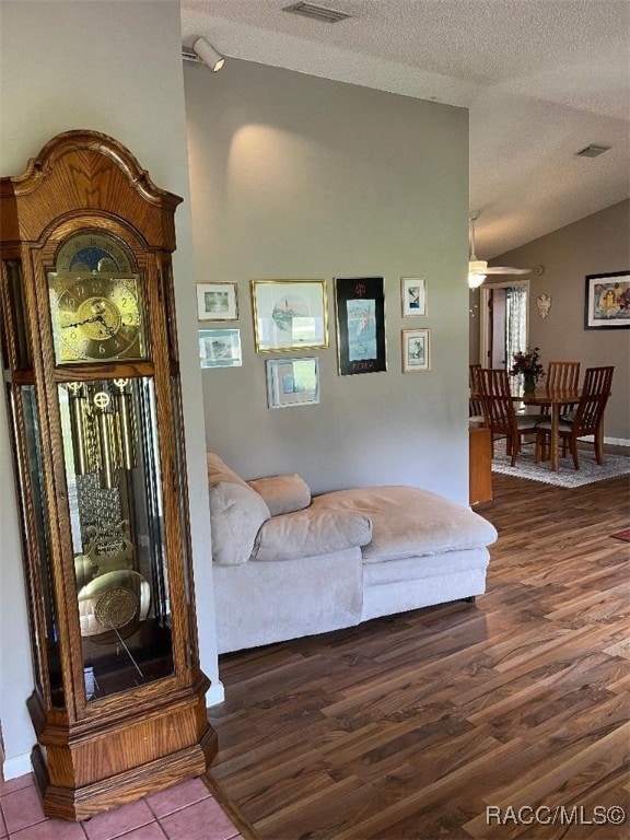 sitting room featuring wood-type flooring, lofted ceiling, and a textured ceiling