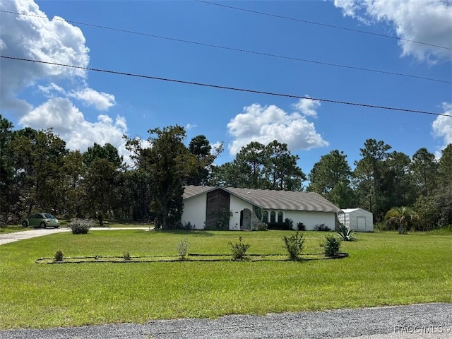 ranch-style house with a front yard and a storage shed