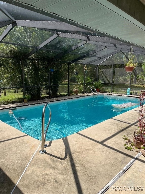 view of swimming pool featuring glass enclosure and a patio area