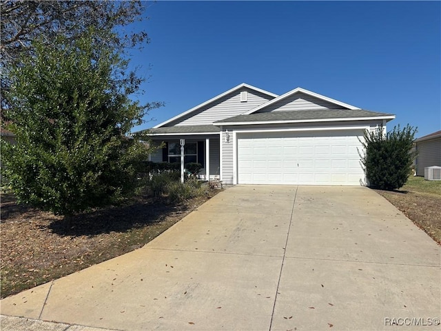 ranch-style home with an attached garage, central air condition unit, and concrete driveway