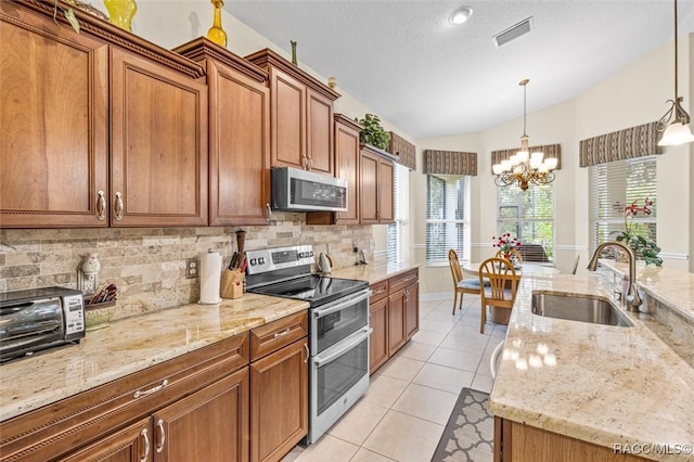 kitchen featuring sink, an inviting chandelier, pendant lighting, vaulted ceiling, and appliances with stainless steel finishes