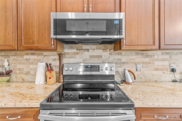 kitchen featuring decorative backsplash, light stone counters, and appliances with stainless steel finishes