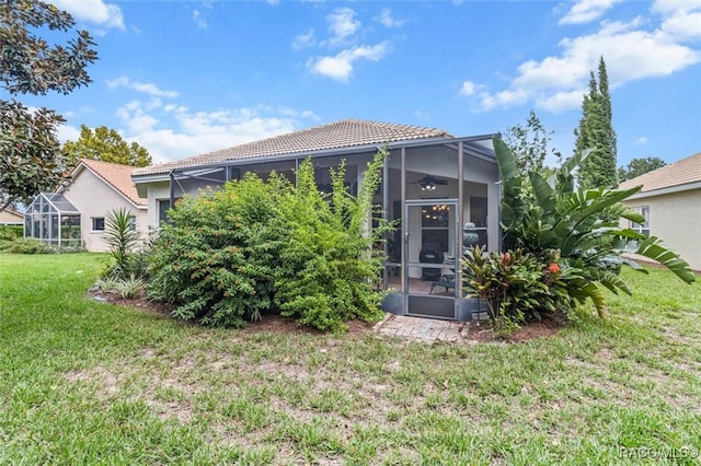 back of house with a sunroom and a lawn