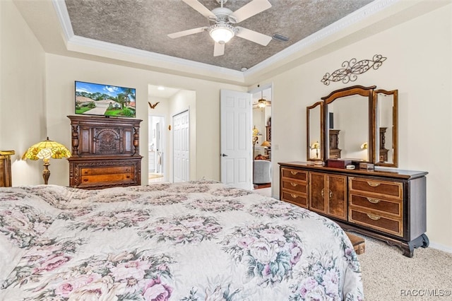 bedroom with carpet flooring, ceiling fan, a textured ceiling, and a tray ceiling