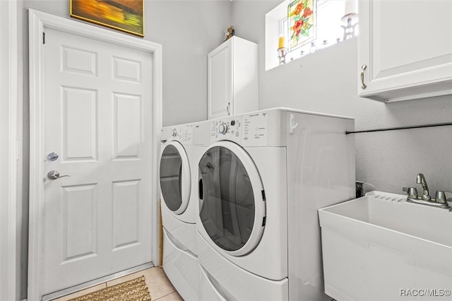 clothes washing area featuring washer and dryer, sink, light tile patterned floors, and cabinets