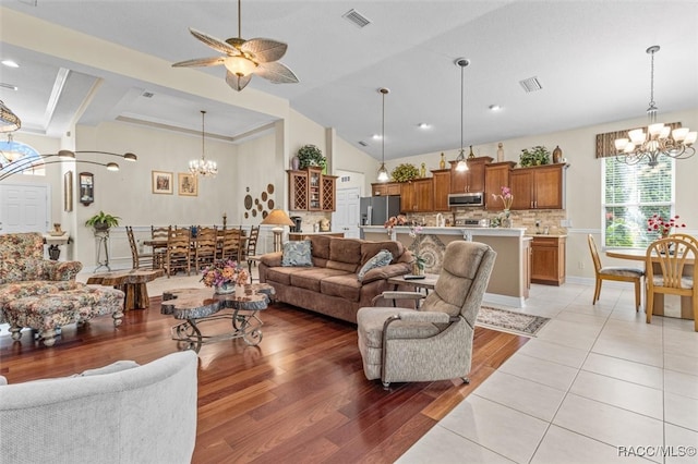 living room featuring ceiling fan with notable chandelier, beam ceiling, light wood-type flooring, and high vaulted ceiling