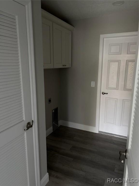 laundry room featuring electric dryer hookup, dark wood-style flooring, cabinet space, and baseboards