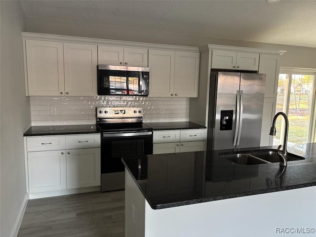 kitchen featuring dark wood finished floors, tasteful backsplash, appliances with stainless steel finishes, white cabinets, and a sink