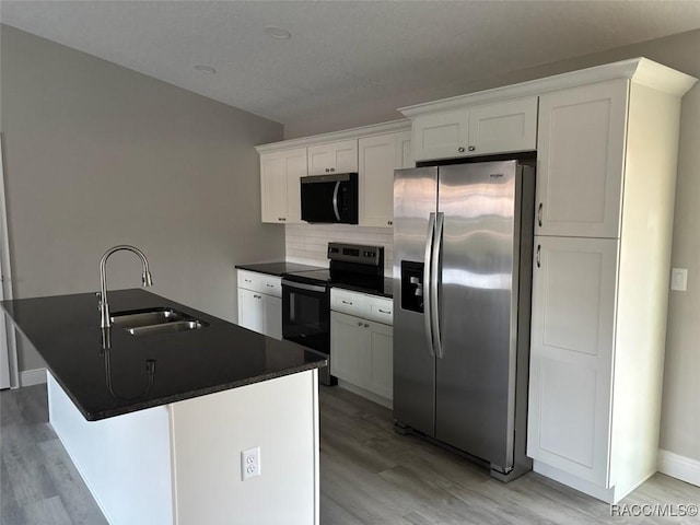 kitchen with white cabinets, dark countertops, black range with electric cooktop, stainless steel refrigerator with ice dispenser, and a sink