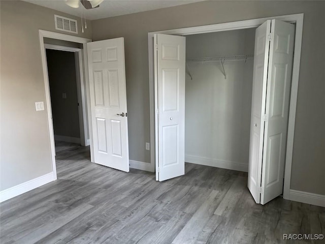 unfurnished bedroom with a closet, light wood-type flooring, visible vents, and baseboards