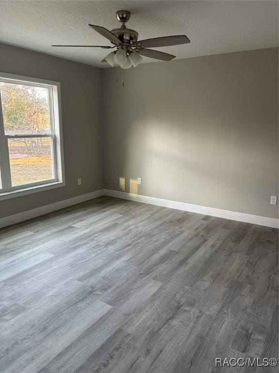 spare room featuring a textured ceiling, ceiling fan, wood finished floors, and baseboards