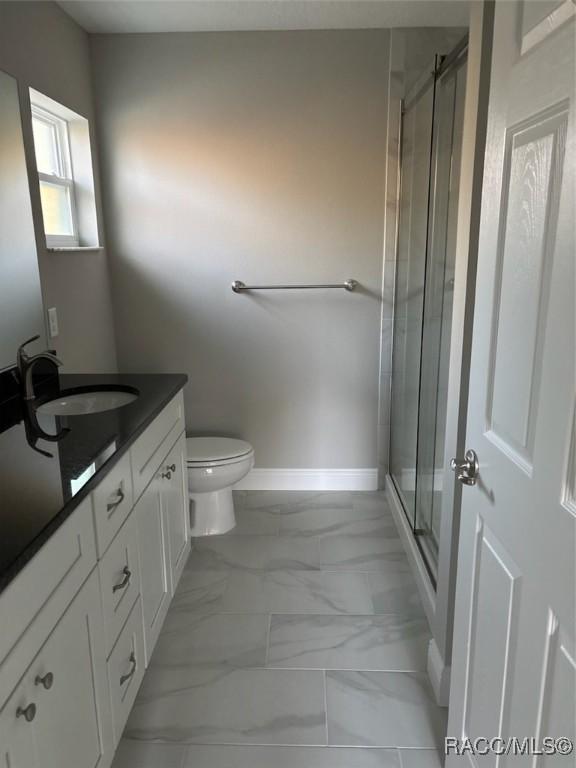 full bath featuring toilet, vanity, baseboards, marble finish floor, and a stall shower