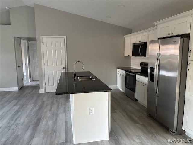 kitchen featuring a sink, white cabinetry, appliances with stainless steel finishes, dark countertops, and a center island with sink