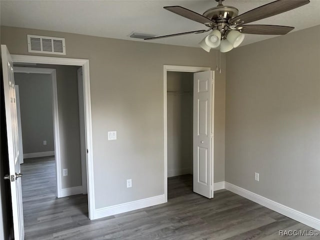 unfurnished bedroom with dark wood-style flooring, visible vents, and baseboards