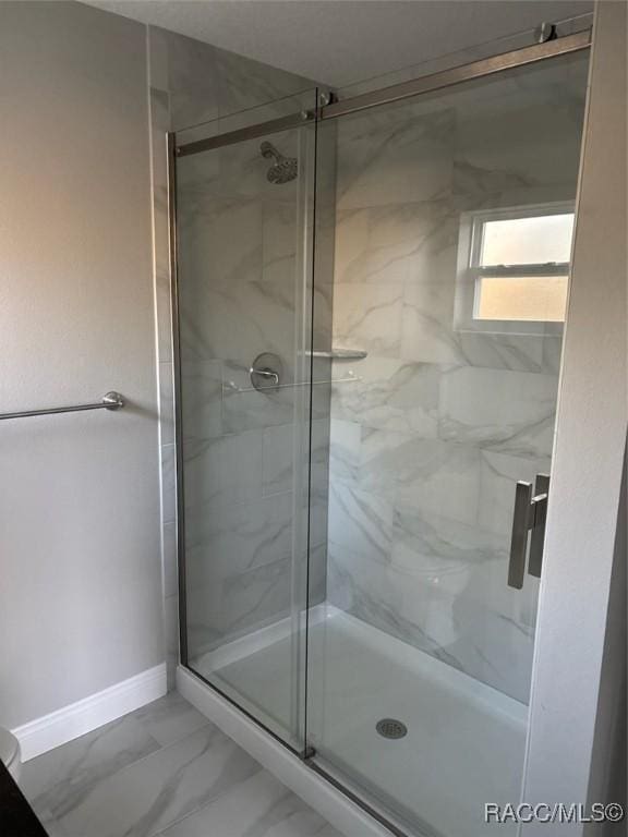 bathroom with a marble finish shower, marble finish floor, and baseboards