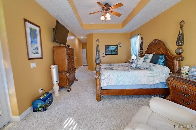 carpeted bedroom with ceiling fan, a textured ceiling, and a tray ceiling