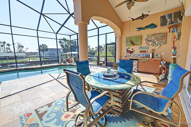 view of patio / terrace featuring ceiling fan, exterior bar, and glass enclosure