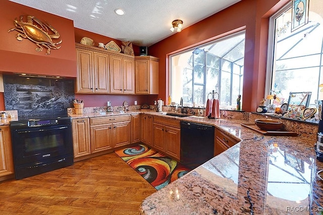 kitchen with sink, light stone counters, black appliances, light hardwood / wood-style floors, and a textured ceiling