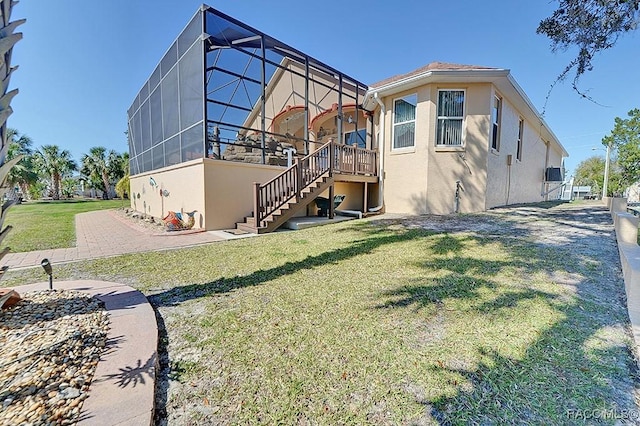 back of house with a lanai, a patio, and a lawn