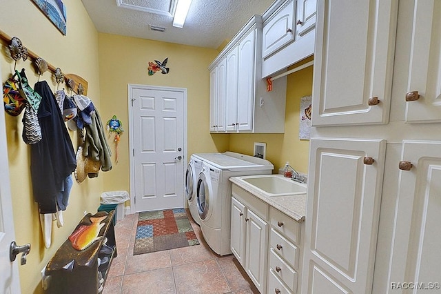 laundry room featuring sink, cabinets, washer and dryer, light tile patterned floors, and a textured ceiling