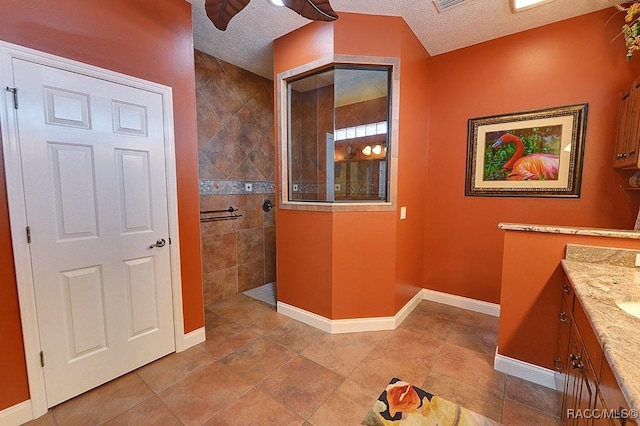 bathroom featuring vanity, a textured ceiling, and tiled shower