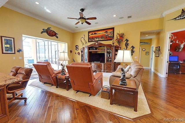 living room featuring wood-type flooring, ornamental molding, ceiling fan, and a textured ceiling