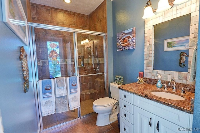 bathroom with tile patterned flooring, vanity, a textured ceiling, a shower with shower door, and toilet