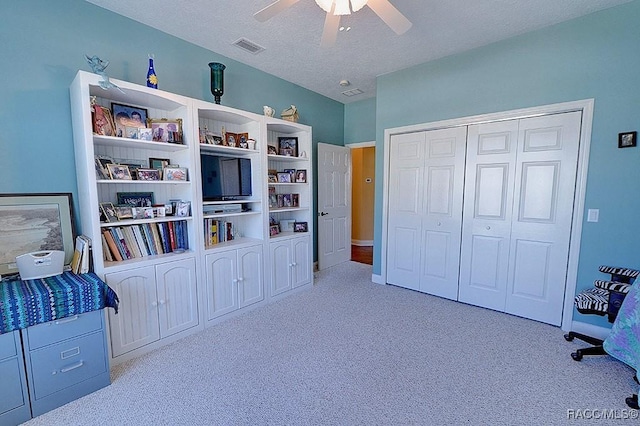 bedroom featuring ceiling fan, light colored carpet, a closet, and a textured ceiling