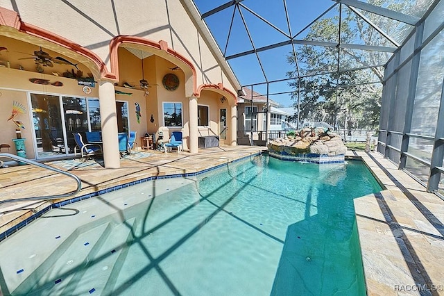 view of swimming pool with ceiling fan, a patio, and glass enclosure