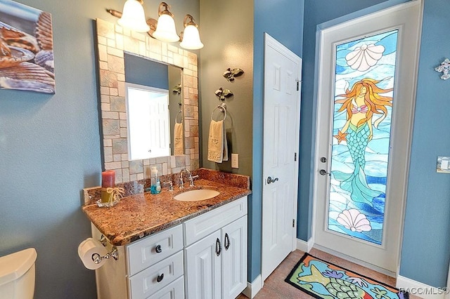 bathroom with plenty of natural light, toilet, and vanity